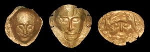 Three Mycenaean masks all of gold.  The middle is the Mask of Agamemnon.  It has much more distinctive features, extended ears, larger eyes, smaller forehead, and a well groomed beard and mustache that is not present on the other two. 